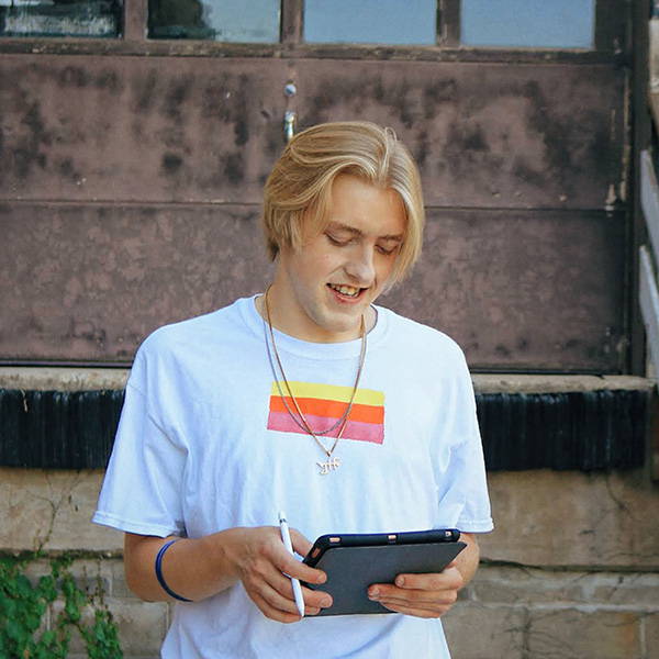A young man holding a tablet in front of a building.