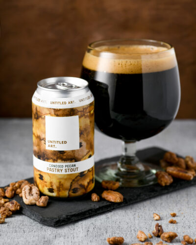A can of beer with nuts and a glass of beer.