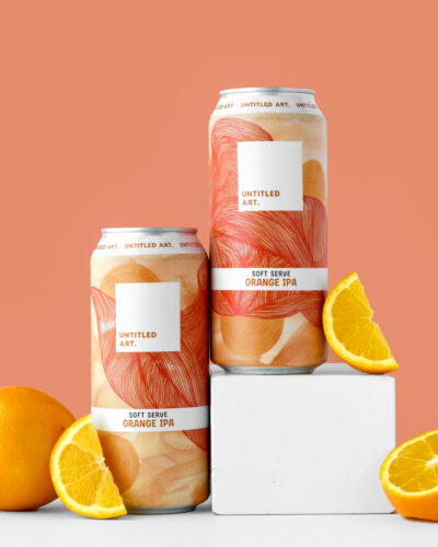 Two cans of beer with orange slices in front of them.