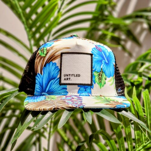 An Untitled Art Patch Logo Tropical Trucker Hat with a tropical flower on it.