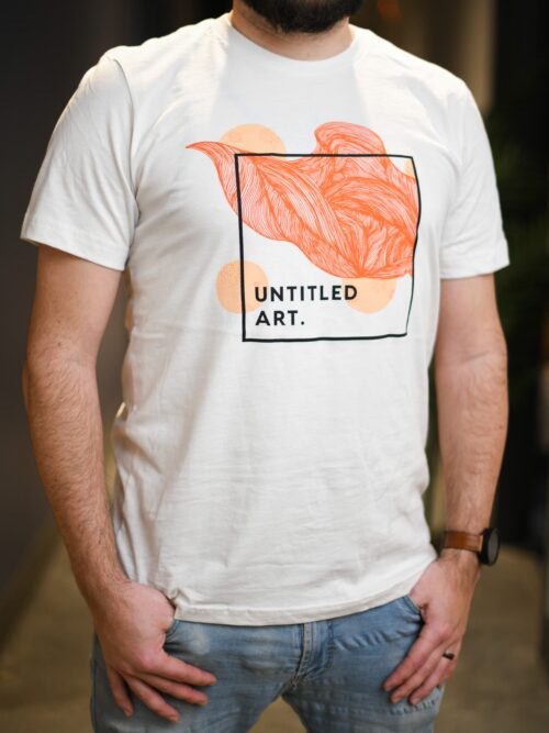 A man wearing a "Soft Serve Orange" T-shirt that says united art.