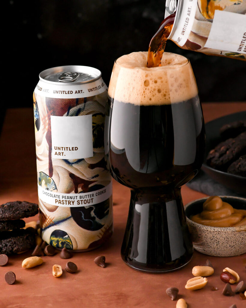 A beer is being poured into a can next to some cookies.