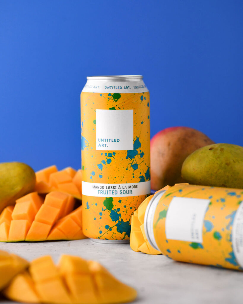 Two cans of mango beer on a blue background.