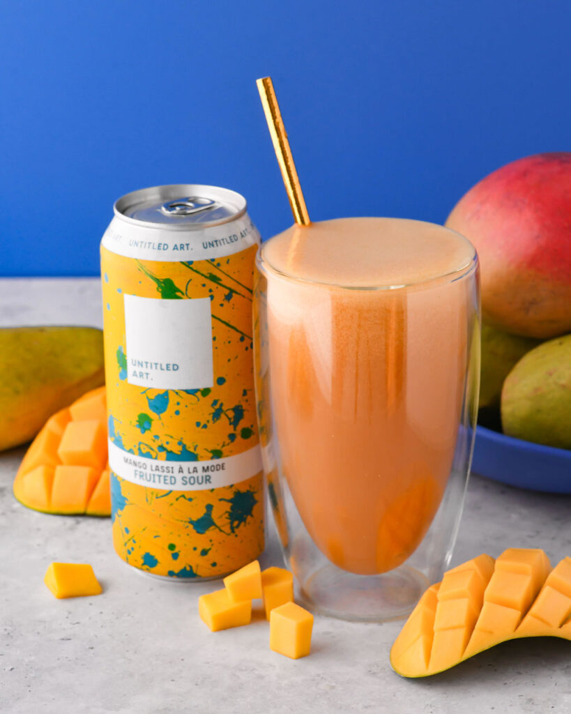 A can of mango iced tea next to a can of mango juice.