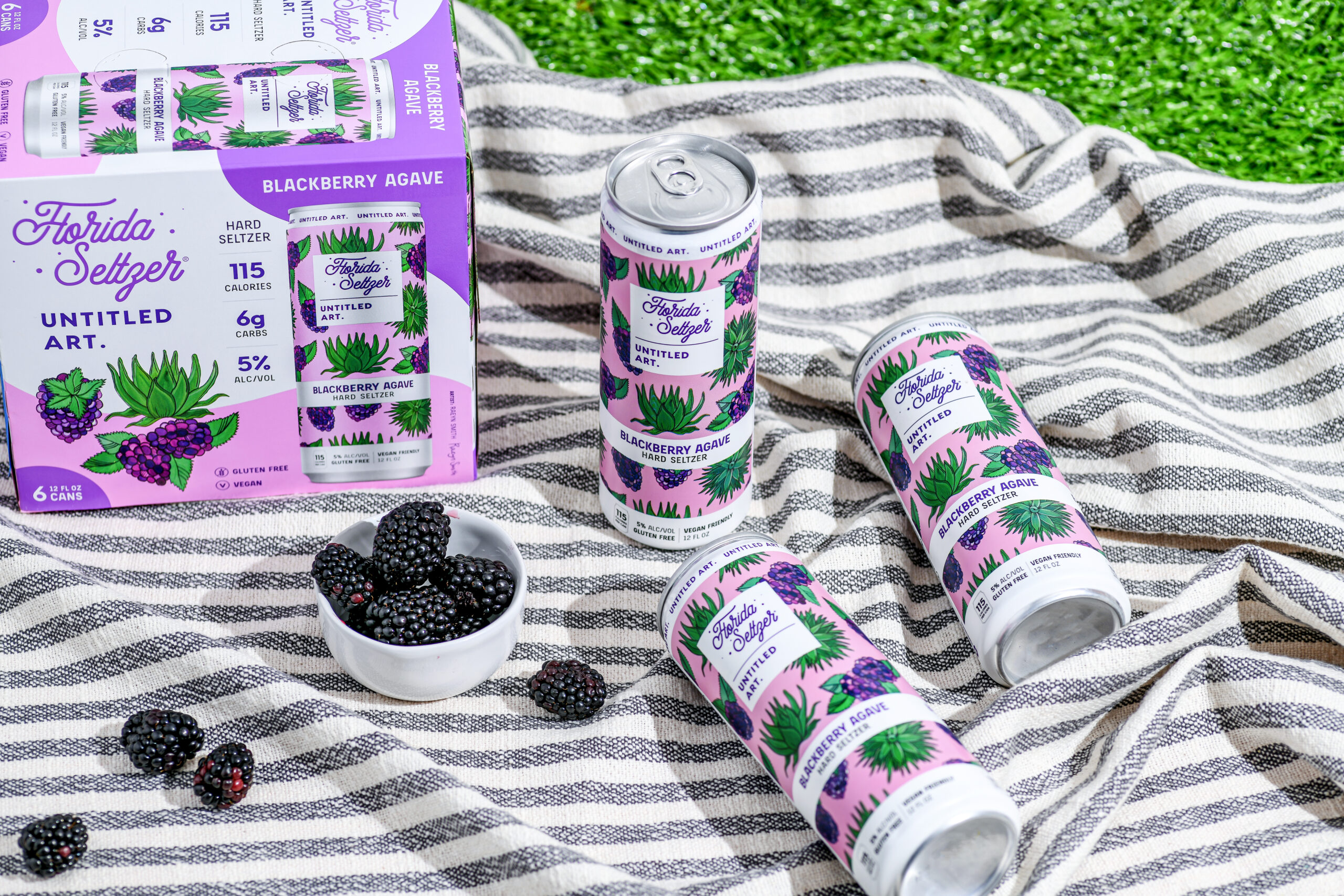 Two cans of blackberry juice on a blanket.