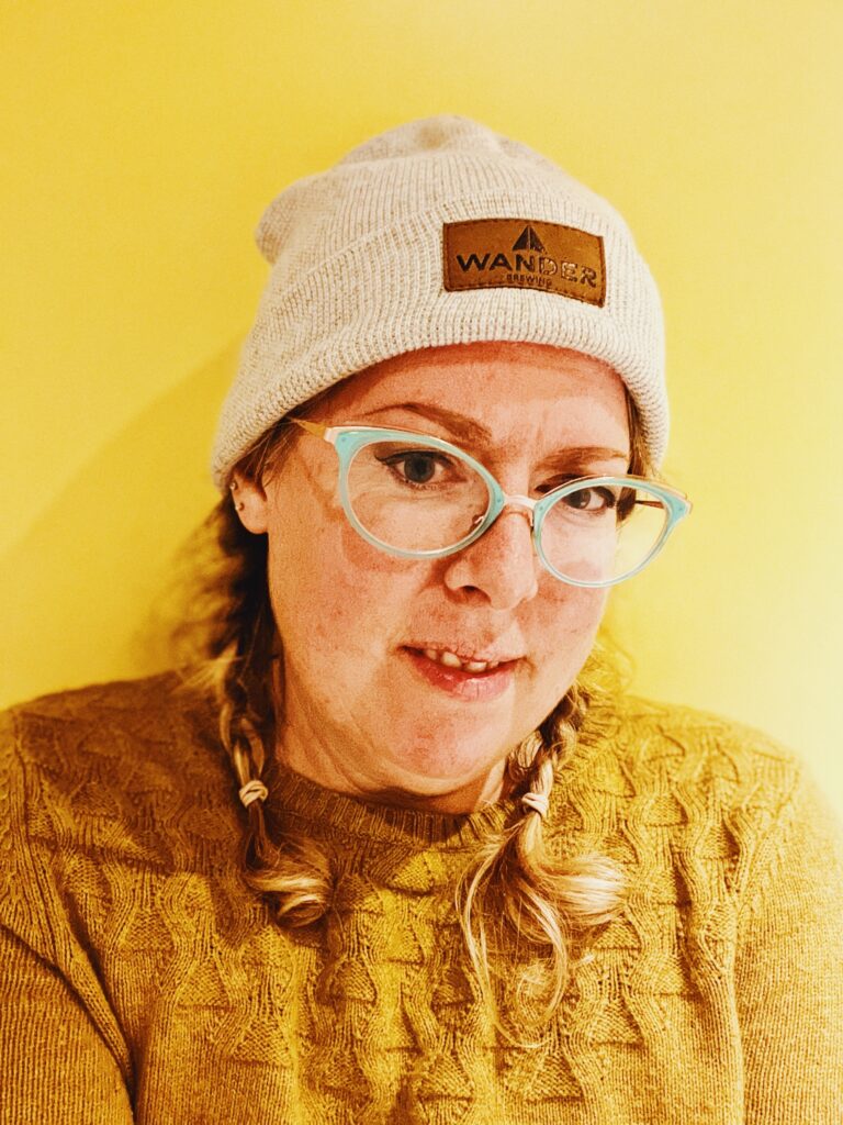 A woman wearing glasses and a beanie.