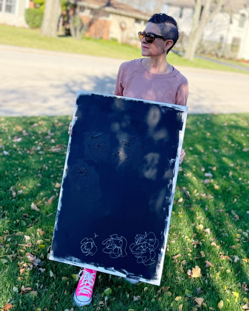 A woman holding up a chalkboard with a drawing on it.